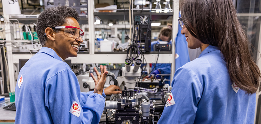 faculty and grad student in a lab in blue lab coats