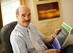 Mark Ratner in his office holding a publication 